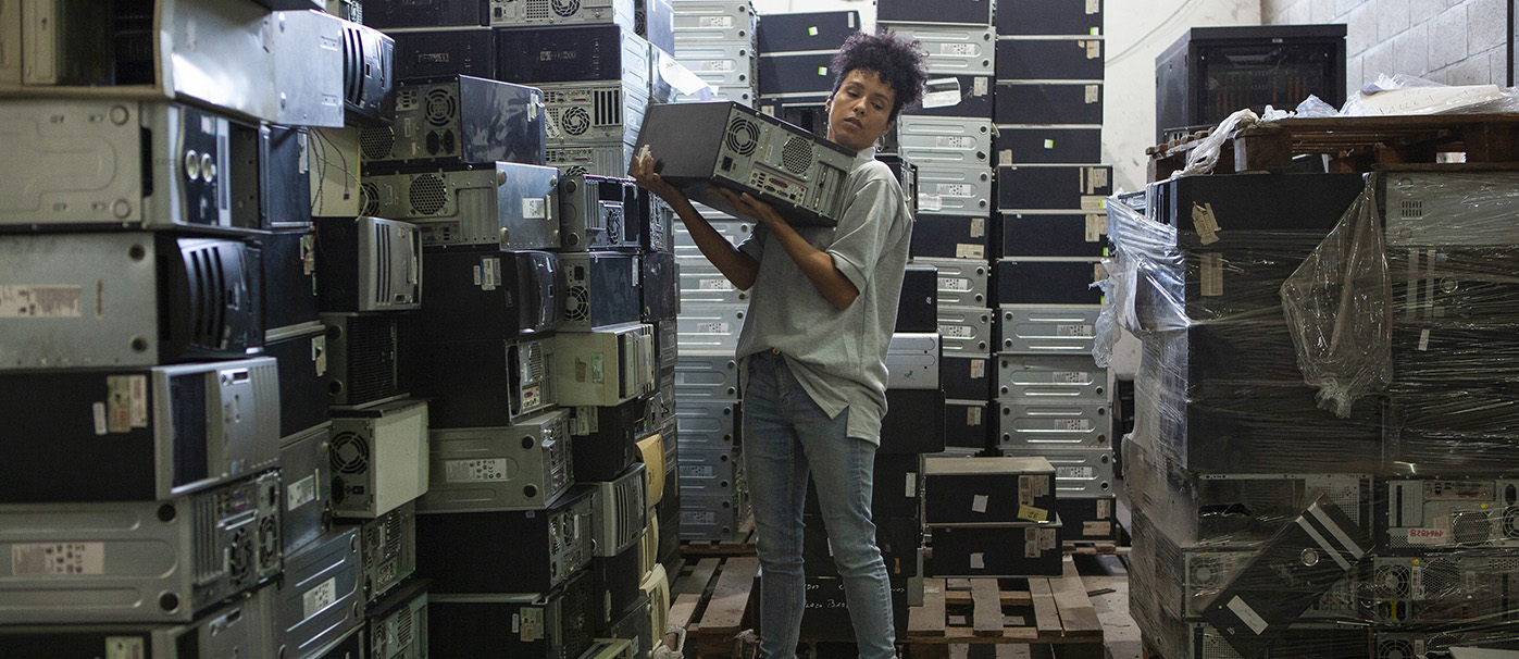 What happens to e-waste in Australia? Wide view of african american female worker sorting obsolete computers components in recycling plant