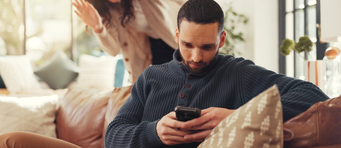 A man using a smartphone on a cozy sofa in a modern living room.