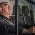 Sleepy man resting in car, possibly driver taking a nap during travel.