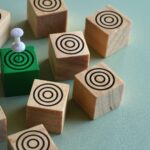 Wooden blocks with target symbols and a green block with a pin on a light background.
