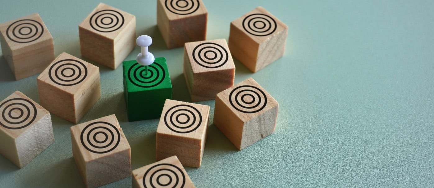 Wooden blocks with target symbols and a green block with a pin on a light background.