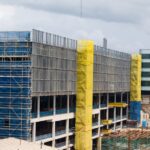 A construction site with a building under development, scaffolding, and a crane in an urban area.
