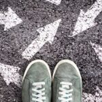 A woman standing on a chalk-drawn arrow parking lot with sneakers.