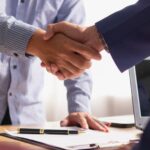 Professional handshake between two businesspeople in an office setting, symbolising partnership and.